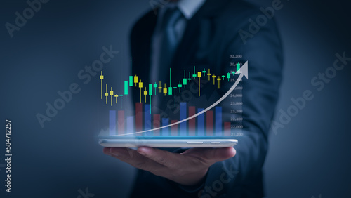 Investor or trader using tablet showing hologram stock chart and growth graph with virtual screen, investment planning and strategy concepts, stock market, mutual funds, bonds, digital assets