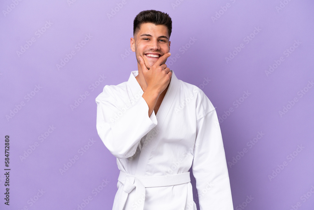 Young caucasian man doing karate isolated on purple background happy and smiling Young caucasian man doing karate isolated on purple background happy and smiling
