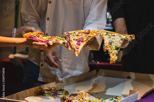 Group of unrecognizable peoples hands holding a slice of pizza.