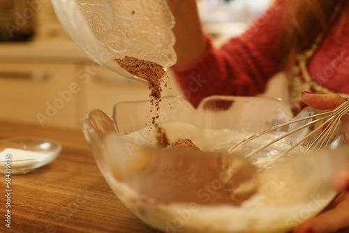 Close-up view of adding cocoa powder to the pastry dough. The moment of spilling the cocoa powder while making the cookie dough.