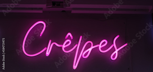 pink neon sign crepes on a cafe