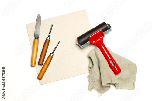 Photos Rodillo de grabado junto a una plancha de linóleo y gubias sobre un fondo blanco liso y aislado