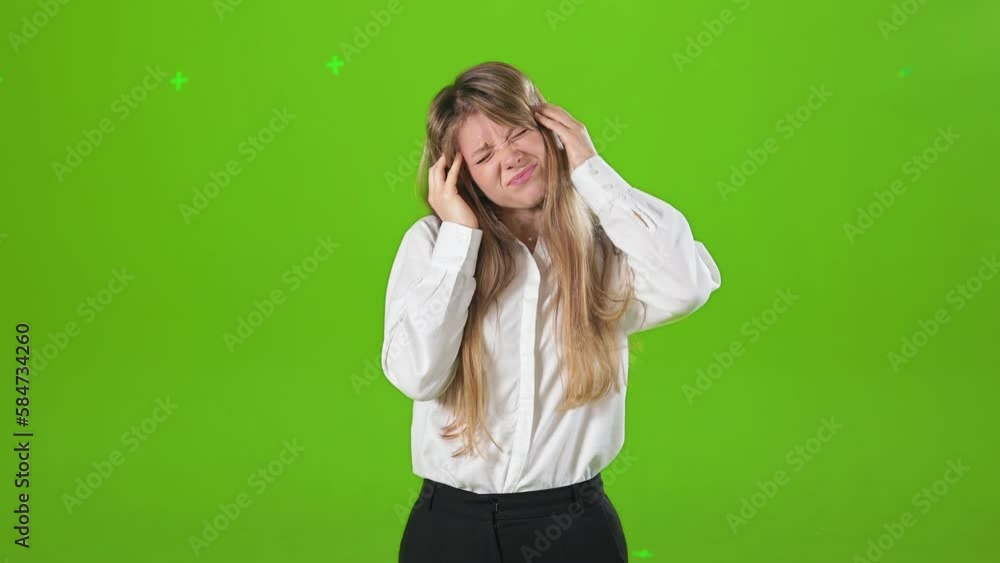 Front view of young, blonde lady, standing, posing in studio, having headache. Tired, hardworking lady looking at camera, touching head. Isolated on green studio background. Front view of young, blonde lady, standing, posing in studio, having headache. Tired, hardworking lady looking at camera, touching head. Isolated on green studio background.