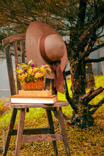 still life book, flowers, hat on chair in the garden
