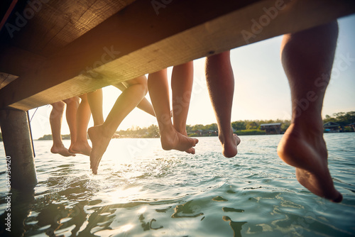 Canvas Print Rear view of legs of group of friends by lake