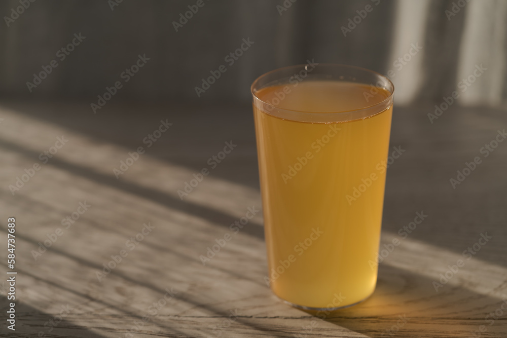 Ginger beer in tumbler glass on white oak table wuth sunlight Ginger beer in tumbler glass on white oak table wuth sunlight