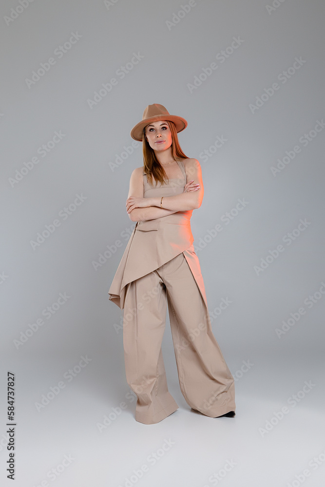 Young woman in beige suit and beige hat standing with crossed arms Young woman in beige suit and beige hat standing with crossed arms