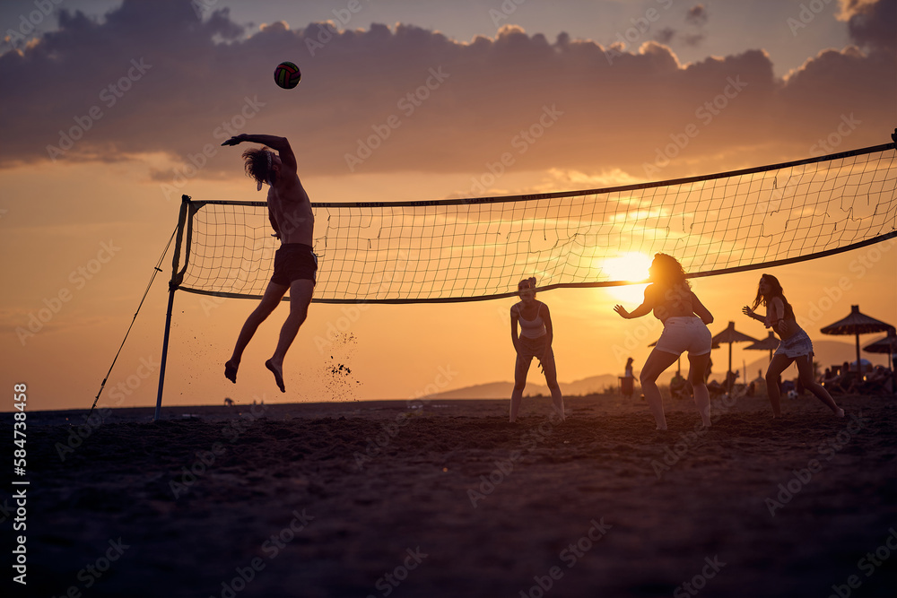 © luckybusiness - A group of friends is playing the volleyball on the beach while sun is setting. Sport, sea, beach