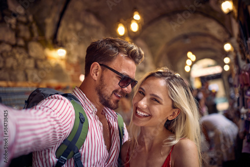 A young couple is taking a selfie while walking the old city during a vacation on the seaside. Vacation, seaside, relationship, tourists © luckybusiness