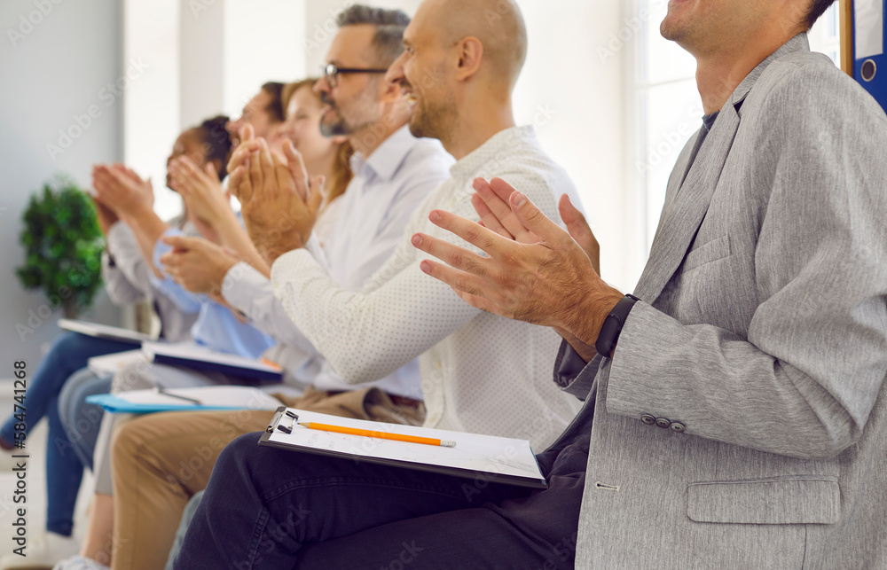 Fototapeta premium Business audience applauding. Happy people with clipboards and pencils sitting in row at business conference and clapping hands for professional speaker after interesting workshop and presentation
