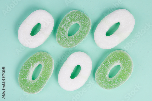 Top view of green and white jelly candies on aquamarine background