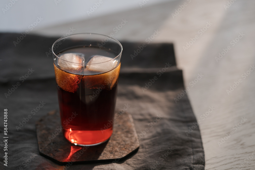 Cola with ice in tumbler glass on wood table with copy space