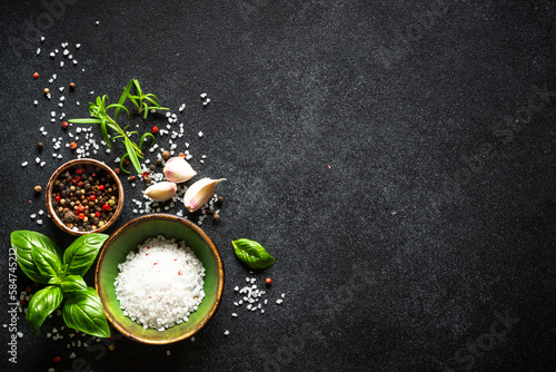 Food cooking background with spices and basil at black. Top view with copy space.