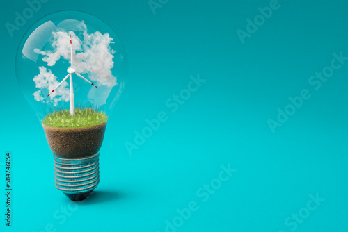 single lightbulb with minature wind turbine inside  green soil and clouds  renewable clean energy concept  3D Illustration © Imillian