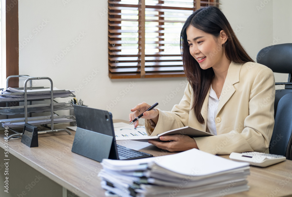 Young Asian businesswoman taking notes using a tablet at the modern office. Young Asian businesswoman taking notes using a tablet at the modern office.