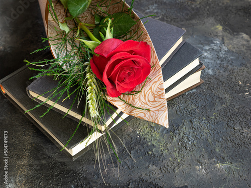 Stack of books and red rose with ear of corn, traditional Sant Jordi gift, Sant Jordi's day. Copy space. photo