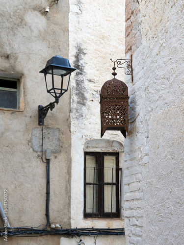 Typical street lamp in a small street of white houses that contrasts with an old wooden street lamp. photo