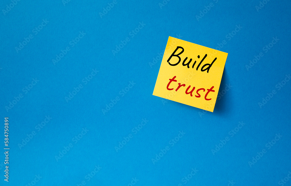 Build trust symbol. Orange steaky note with words Build trust. Beautiful blue background. Business and Build trust concept. Copy space. Build trust symbol. Orange steaky note with words Build trust. Beautiful blue background. Business and Build trust concept. Copy space.
