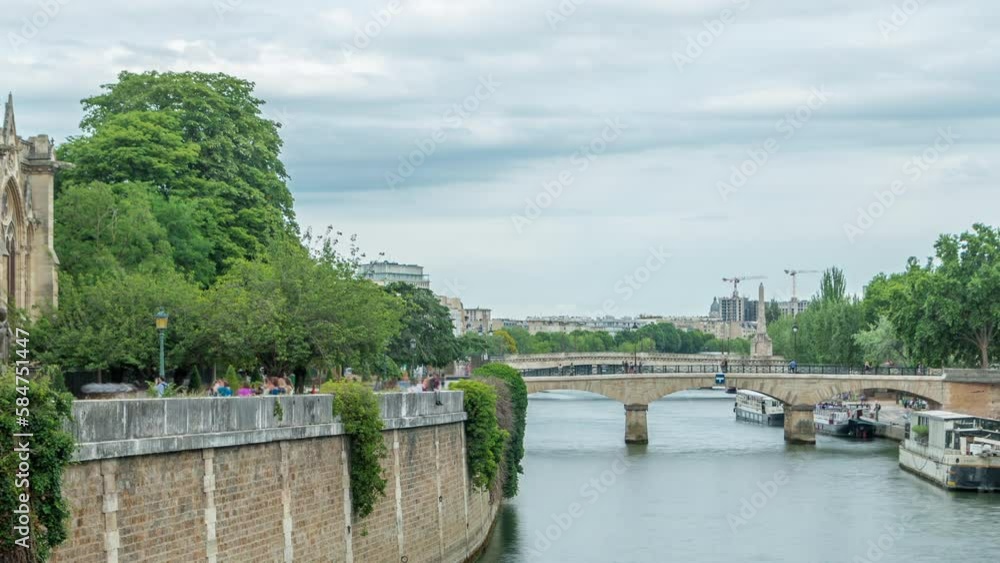 Notre Dame de Paris Garden on Cite Island timelapse, Paris, France. Park with green trees and flowers. View from Double bridge. River with floating boats. Cloudy sky at summer day Notre Dame de Paris Garden on Cite Island timelapse, Paris, France. Park with green trees and flowers. View from Double bridge. River with floating boats. Cloudy sky at summer day