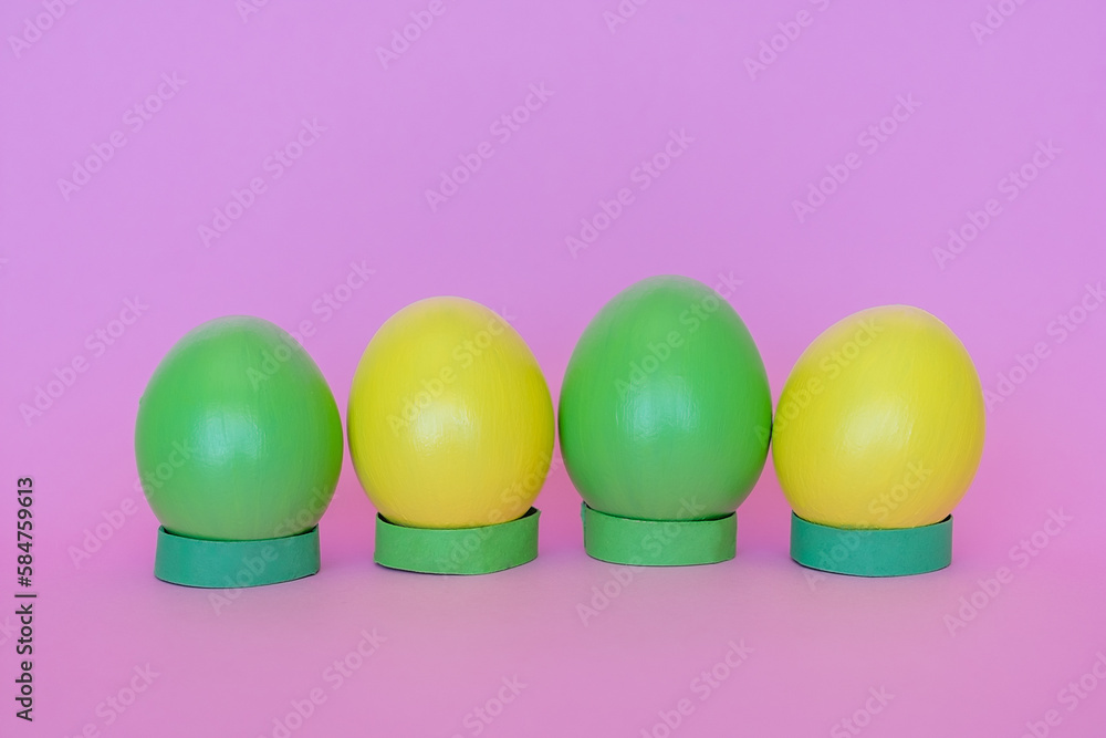 Easter eggs in a vertical position of yellow and green on a pink background. Easter eggs in a vertical position of yellow and green on a pink background.
