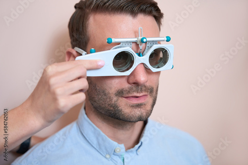 Handsome Caucasian man in trial frame is checking visual acuity in the clinic