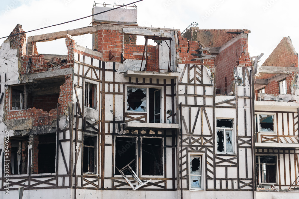 Destroyed building after russian invasion, Gostomel, Ukraine. Ruined facade of house with fachwerk design. War in Ukraine. Broken windows and brick walls after missile attack. Abandoned damaged home.