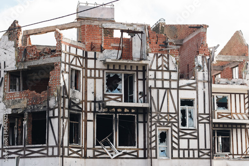Destroyed building after russian invasion, Gostomel, Ukraine. Ruined facade of house with fachwerk design. War in Ukraine. Broken windows and brick walls after missile attack. Abandoned damaged home.