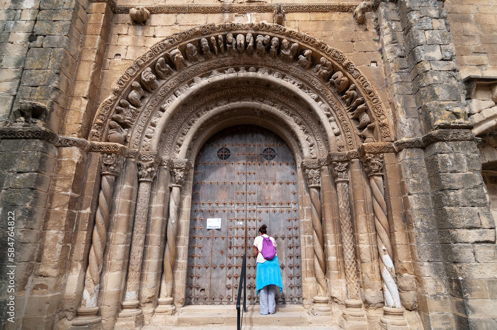 Una turista en la portada románica de la iglesia de Uncastillo en Aragón, España.