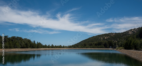 Panoramic view of dam full of water in the forest . Water reservoir