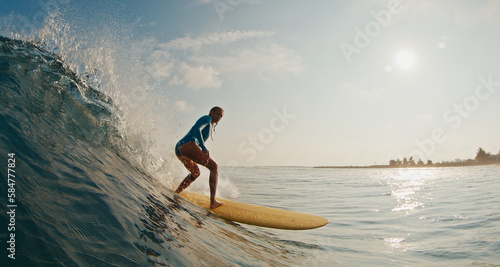 Slim woman surfer rides the wave. Woman surfs the ocean wave in the Maldives on yellow longboard © Dudarev Mikhail