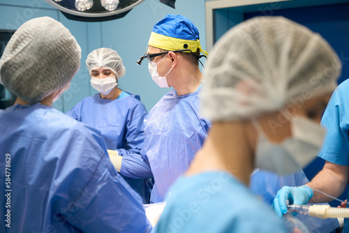 Doctors surgeons, anesthesiologist perform operation in sterile operating room