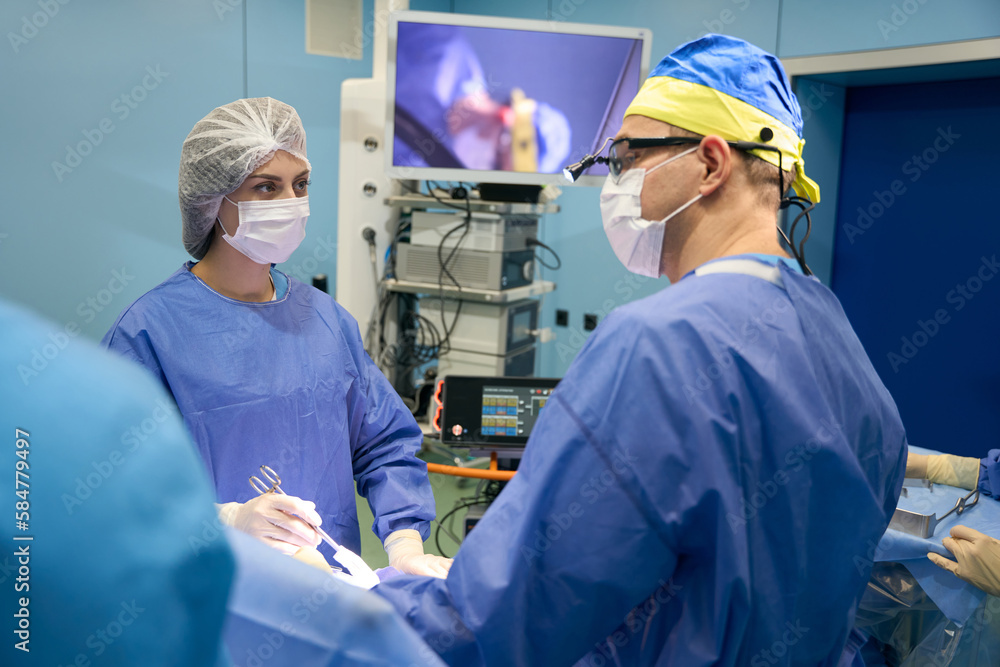 Surgeon with assistants operates on patient in sterile operating room Surgeon with assistants operates on patient in sterile operating room