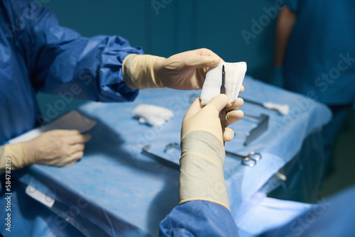 Colleague assistant in operating room passes the scalpel to surgeon