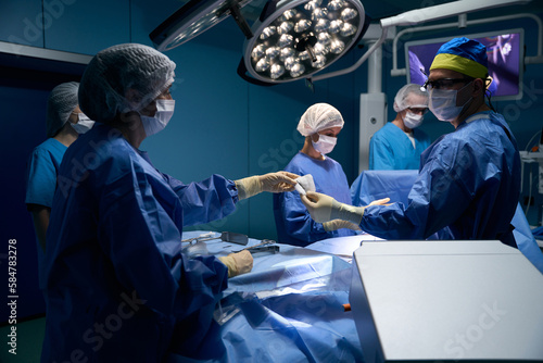 Female assistant gives the surgeon an instrument during the operation