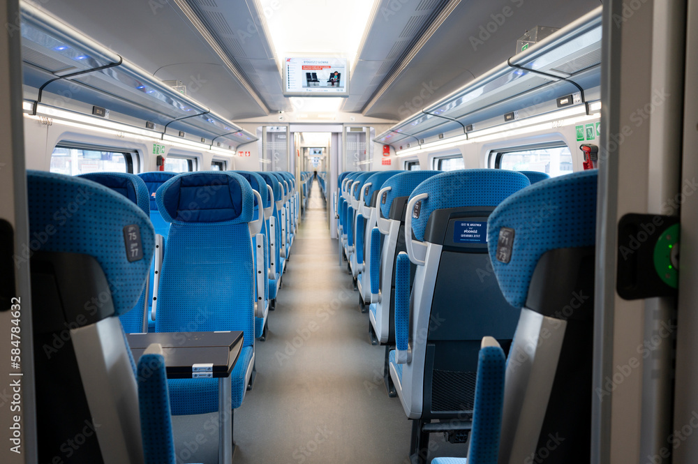 Empty cabin of a modern passenger train. Empty blue seats inside train cabin, corridor view, no people. Modern european economy class fast train interior. Inside of high speed train compartment