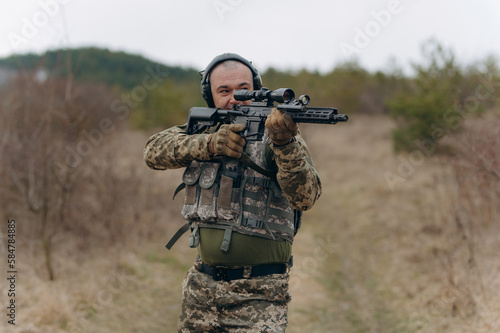 a soldier fires a machine gun. a military man in a balaclava takes aim at the enemy