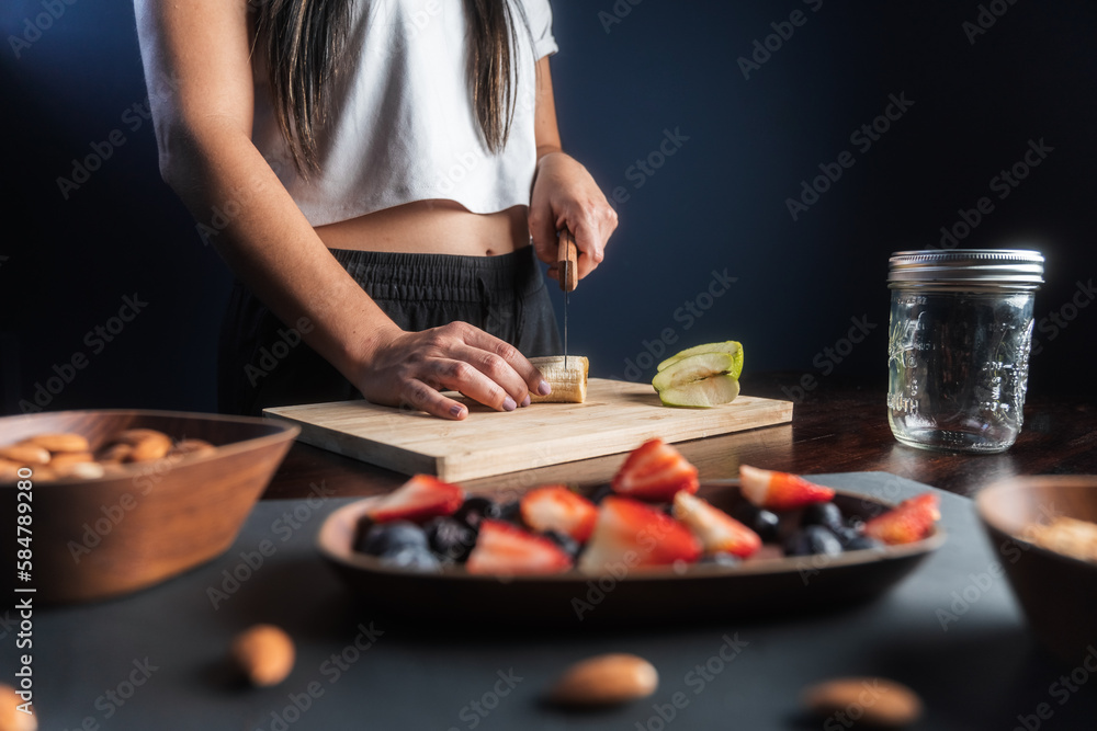 Woman prepares ingredients for a healthy fruit snack in her home kitchen Woman prepares ingredients for a healthy fruit snack in her home kitchen