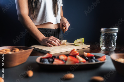 Woman prepares ingredients for a healthy fruit snack in her home kitchen