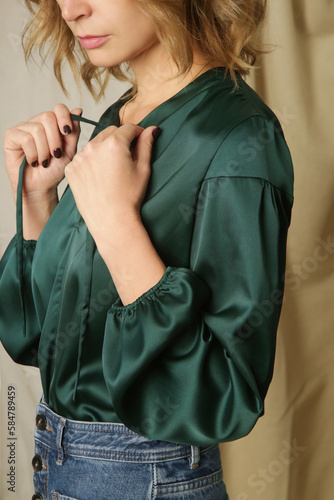 Serie of studio photos of young female model in pine green silk blouse and relaxed jeans