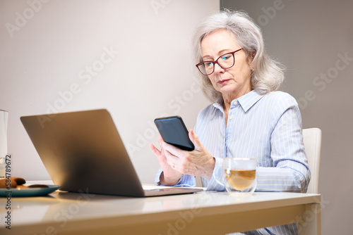 Serious lady with glasses settled down with laptop at kitchen table