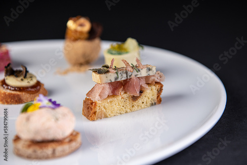 Photography focus on various gastronomic appetizer on a white plate and black background,cul