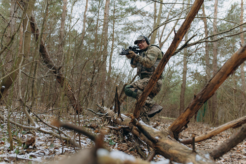 military man in camouflage uniform on tree branches, in an ambush with a weapon, a machine gun.