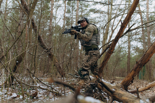 military man in camouflage uniform on tree branches, in an ambush with a weapon, a machine gun.