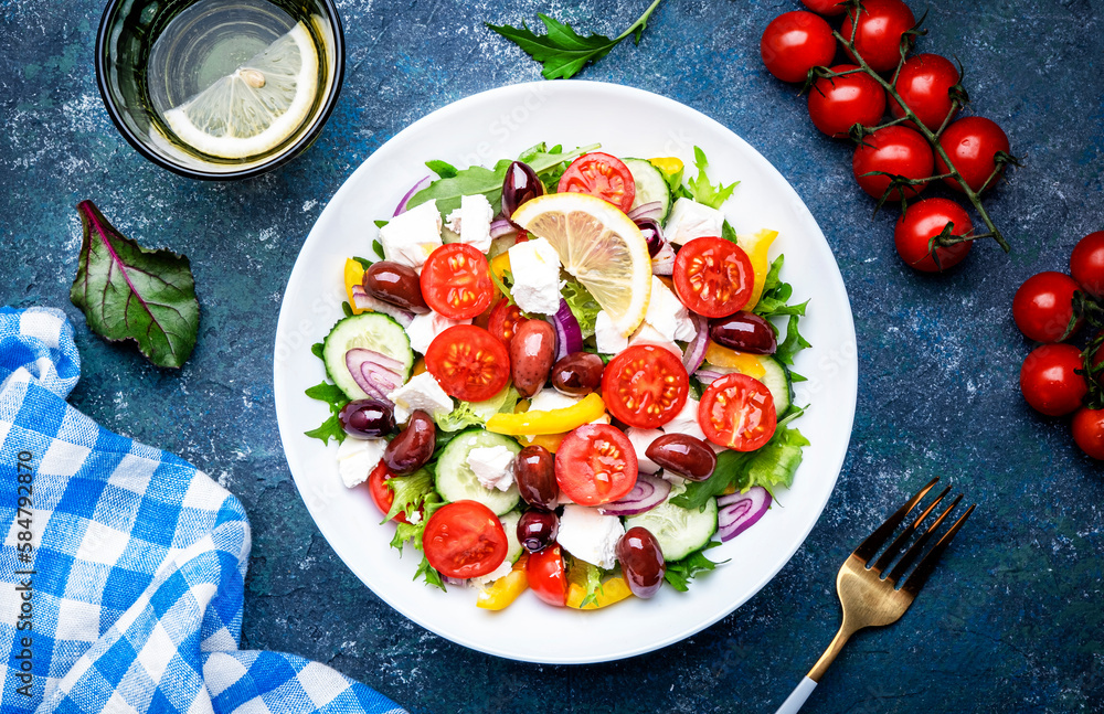 Greek salad with feta cheese, kalamata olives, red tomato, yellow paprika, cucumber and onion, healthy mediterranean diet food, low calories eating. Blue stone background, top view Greek salad with feta cheese, kalamata olives, red tomato, yellow paprika, cucumber and onion, healthy mediterranean diet food, low calories eating. Blue stone background, top view