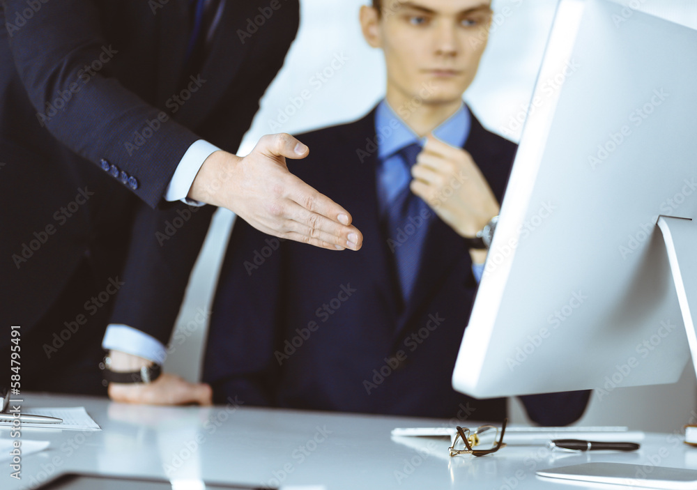 Two businessmen discussing questions at meeting in a modern office, using a computer. Headshot at negotiation or workplace. Teamwork, partnership and business concept Two businessmen discussing questions at meeting in a modern office, using a computer. Headshot at negotiation or workplace. Teamwork, partnership and business concept