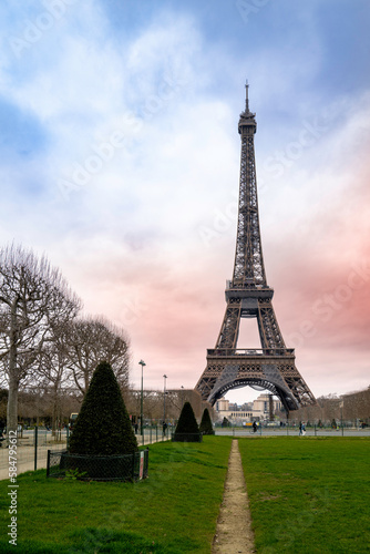 The Eiffel Tower over the green lawn field of Champ de Mars, Field of Mars, in Paris, France
