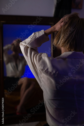 Unrecognizable woman in reflection in front of a mirror in a dark room.