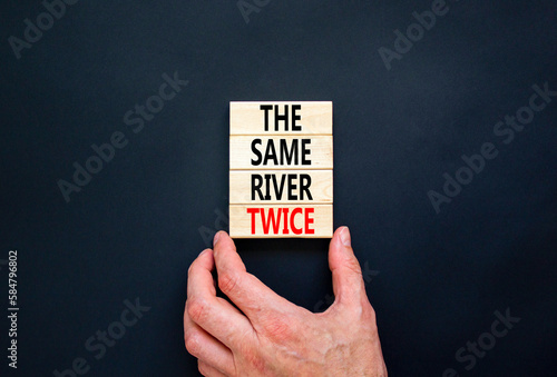 The same river twice symbol. Concept words The same river twice on wooden block. Beautiful black table black background. Businessman hand. Motivational business same river twice concept. Copy space.