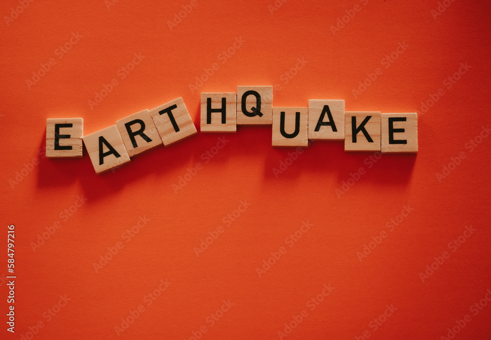 Inscription earthquake from vibration moves on background. Concept of earthquake, destruction and shifts of earth's crust. Wooden square blocks with letters are laid out on orange sheet. Slow motion Inscription earthquake from vibration moves on background. Concept of earthquake, destruction and shifts of earth's crust. Wooden square blocks with letters are laid out on orange sheet. Slow motion