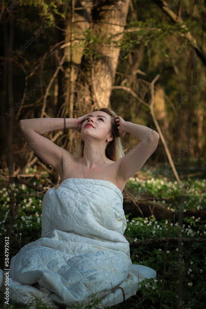 Portrait of a young beautiful fair-haired girl in a white veil in the forest on a meadow with flowers. Portrait of a young beautiful fair-haired girl in a white veil in the forest on a meadow with flowers.